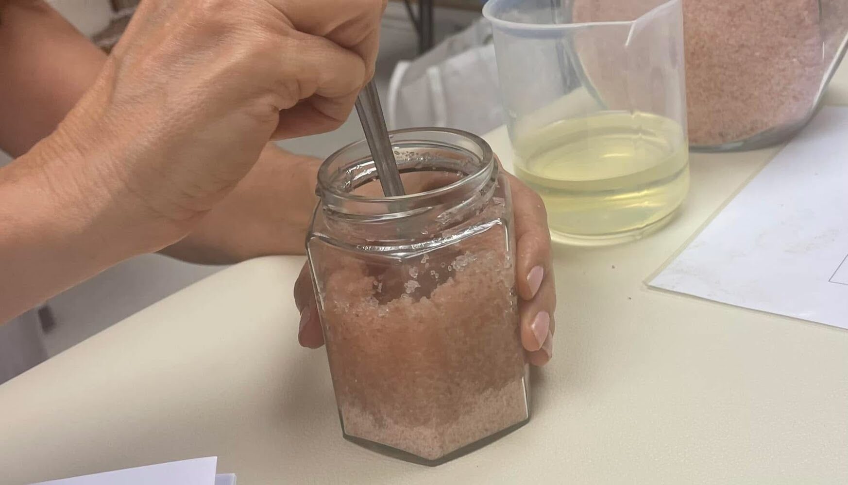 Hands mixing an aromatherapy blend in small glass jars