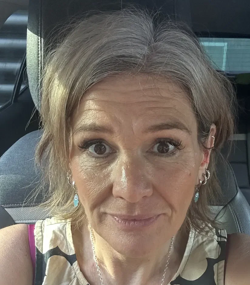 Karen from Done Different smiling, wearing a black and cream flower-print top and silver hamsa earrings