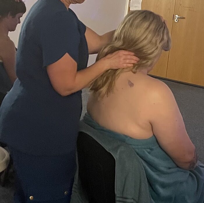 A student practising seated head and shoulder massage on a client during a practical training day