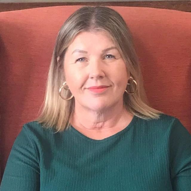 Tracy Ede, counsellor, smiling and sitting in a red armchair