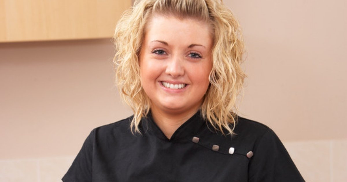 A smiling beauty therapist in a black tunic, ready to start her career in facials and skincare